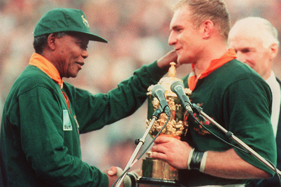 Fotografía tomada el 24 de junio de 1995 en la que el presidente sudafricano Nelson Mandela (izq.) felicita al capitán de la selección de rugby de Sudáfrica, Francois Pienaar (der.), tras la victoria de Sudáfrica en la final de la Copa del Mundo de Rugby contra Nueva Zelanda, en Johannesburgo. El héroe de la lucha contra el apartheid, Nelson Mandela, celebró entonces su 92.º cumpleaños en casa con su familia el 18 de julio de 2010, apenas una semana después de que la Copa del Mundo exhibiera los logros de la Sudáfrica democrática.