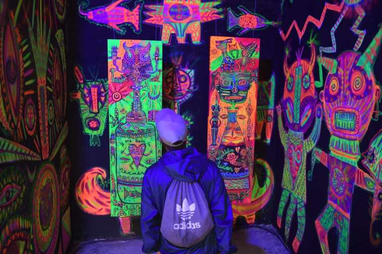 Un hombre viendo una pared pintada con colores de neón