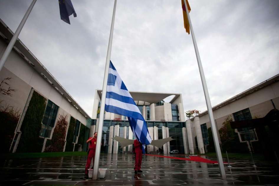 Dos empleados izan una bandera de Grecia (c) frente a la Cancillería Federal en Berlín, Alemania. EFE