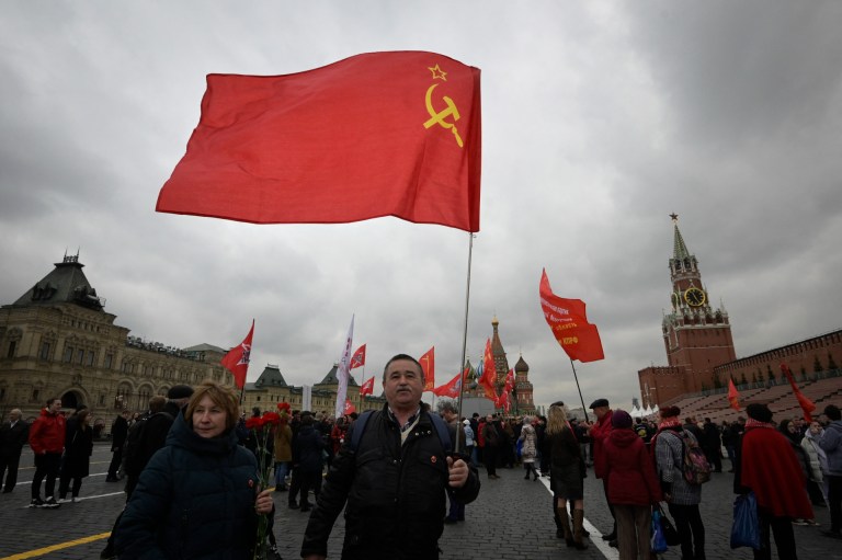 Un hombre sostiene la bandera del comunismo. Muchos  simpatizantes del Partido Comunista Ruso llevaban banderas rojas mientras se dirigían hacia el mausoleo del fundador de la Unión Soviética, Vladímir Ilyich Ulyanov, también conocido como Lenin, para conmemorar 152 años de su nacimiento.