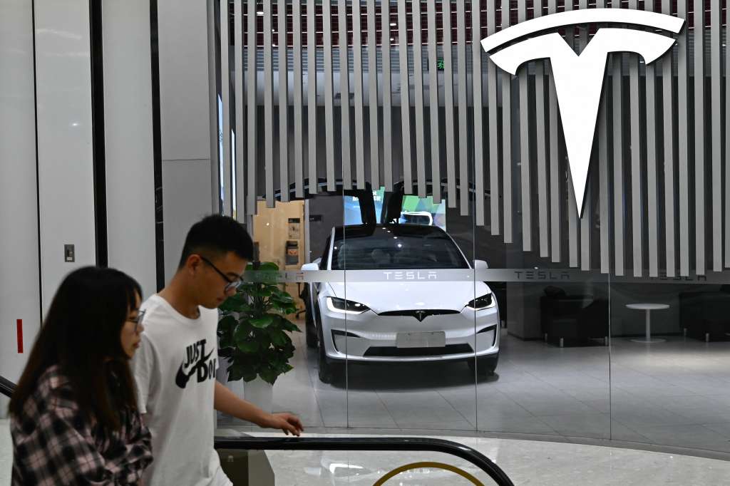 (FILES) People walk past a Tesla shop at a shopping mall in Beijing on July 9, 2024.