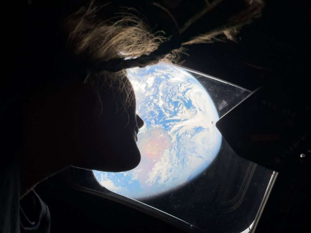 TOPSHOT - This handout picture by an Artemis II crew member provided by NASA shows Artemis II mission specialist Christina Koch looking back at earth through the window of the Orion spacecraft on April 2, 2026.