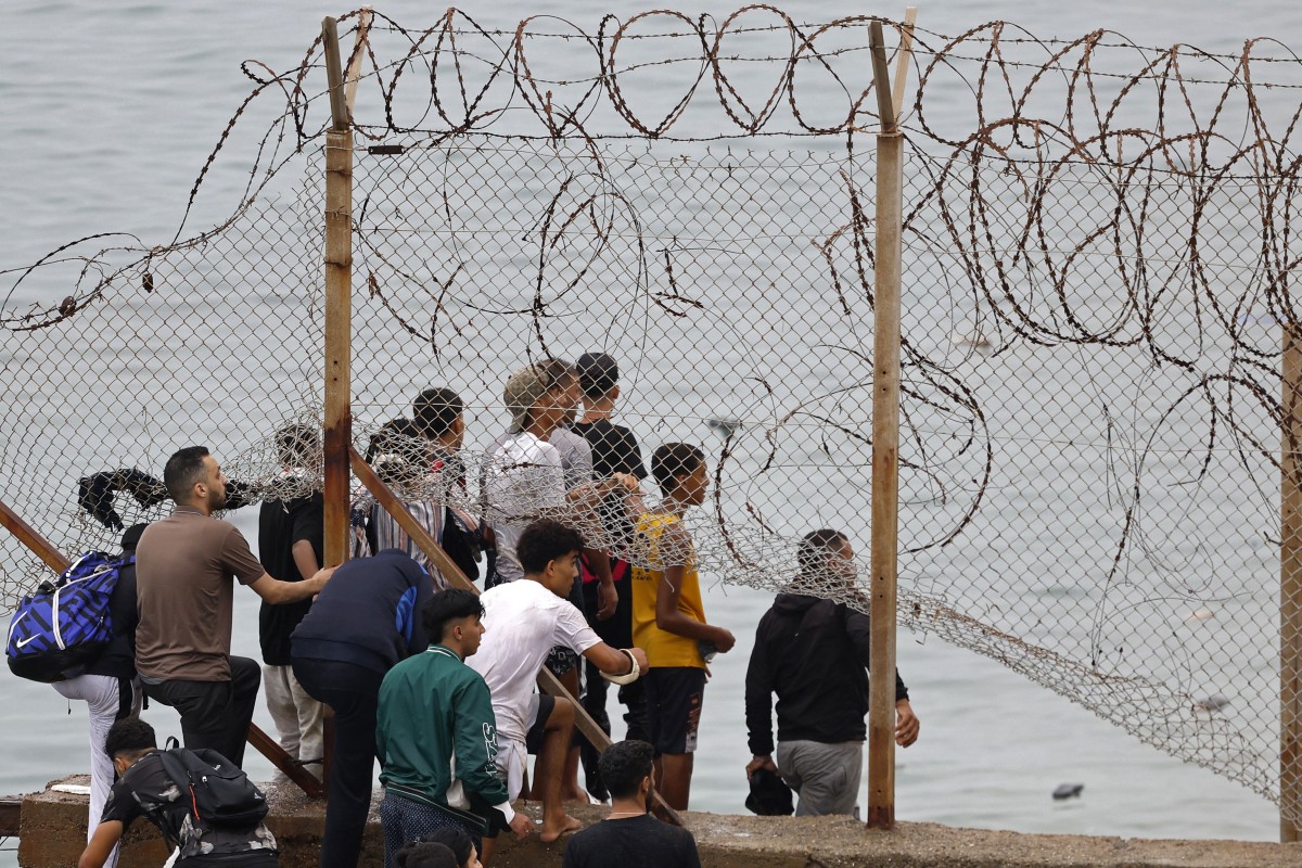 People gather along the fence close to the site of clashes near Fnideq, on the Morocco-Spain border, on July 31, 2026.