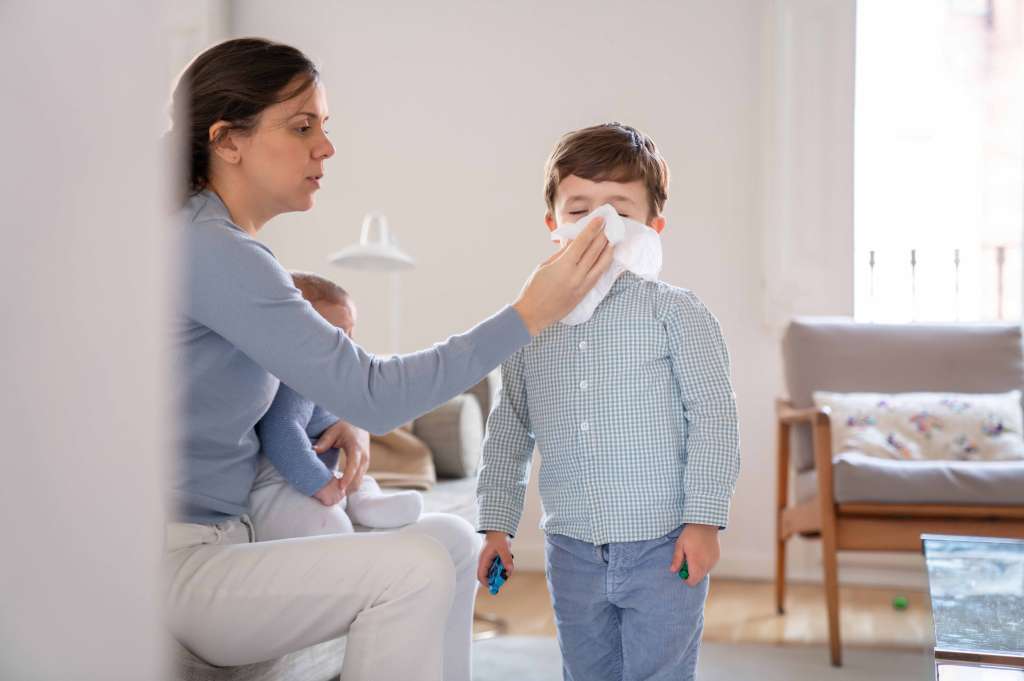 Mamá limpia la nariz de su hijo