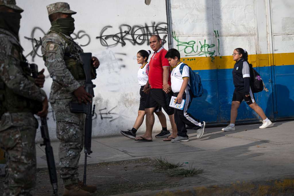 Members of the Peruvian army stand guard as parents drop off their children at the private San Vicente School, that was victim of extortion, in Lima on April 2, 2025.