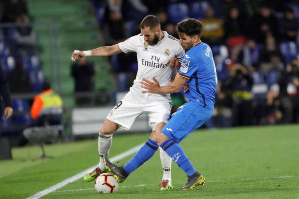 El delantero francés del Real Madrid Karim Benzema (d) lucha con el uruguayo Leandro Cabrera, del Getafe CF, durante el partido de este jueves. / EFE