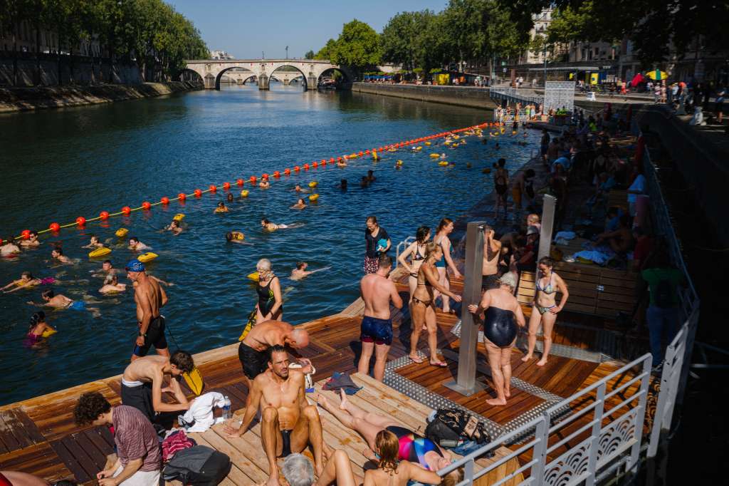 People swim and sunbath at the Bras Marie safe bathing site on the Seine river in Paris on August 12, 2025.