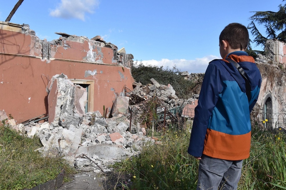 Un niño observa un edificio dañado en la localidad siciliana de Fleri en la provincia de Catania / EFE