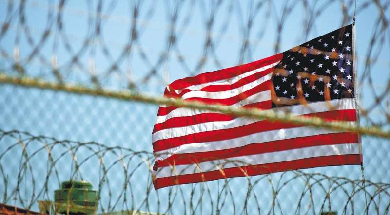 Una bandera estadounidense junto al alambrado del Campo Delta, una de las estaciones de EE. UU. en Guantánamo. / EFE