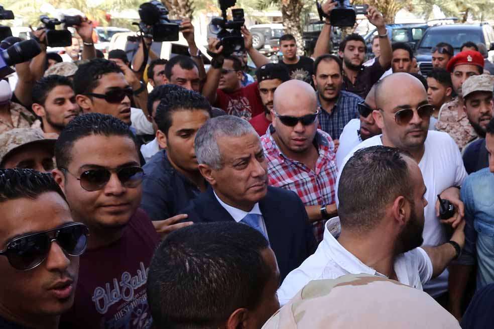 Alí Zeidan, primer ministro libio (centro), regresa a la sede del gobierno en Trípoli después de haber estado secuestrado durante varias horas por un grupo miliciano. / AFP