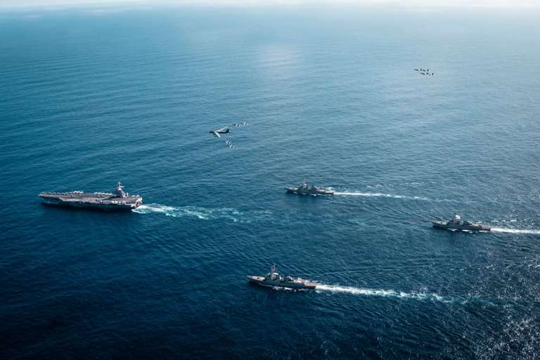 El Grupo de Ataque del Portaaviones Gerald R. Ford de la Armada de los Estados Unidos, que incluye el buque insignia USS Gerald R. Ford (CVN 78), a la izquierda, el USS Winston S. Churchill (DDG 81), al frente, el USS Mahan (DDG 72), atrás, el USS Bainbridge (DDG 96) y los cazas F/A-18E/F Super Hornets, junto a un bombardero B-52 Stratofortress de la Fuerza Aérea de los Estados Unidos.