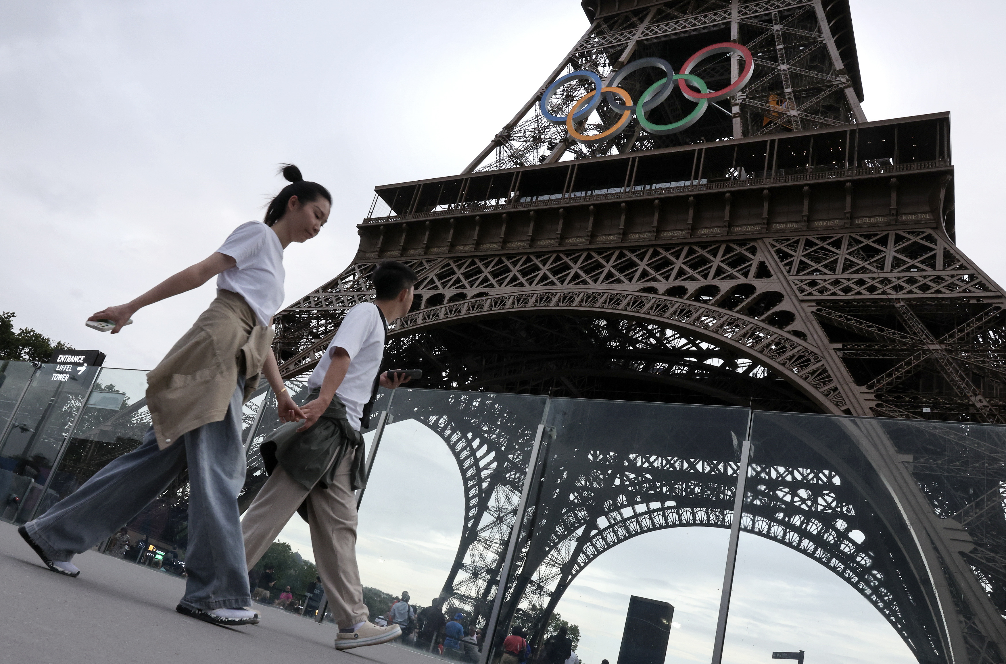 Paris (France), 25/07/2024.- Pedestrians pass by the Eiffel Tower with the Olympic rings prior to the opening ceremony of the Paris 2024 Olympic Games, in Paris, France, 25 July 2024. The opening ceremony of the Paris 2024 Olympic Games will begin on 26 July with a nautical parade on the Seine river and end on the protocol stage in front of the Eiffel Tower. (Francia) EFE/EPA/MAXIM SHIPENKOV