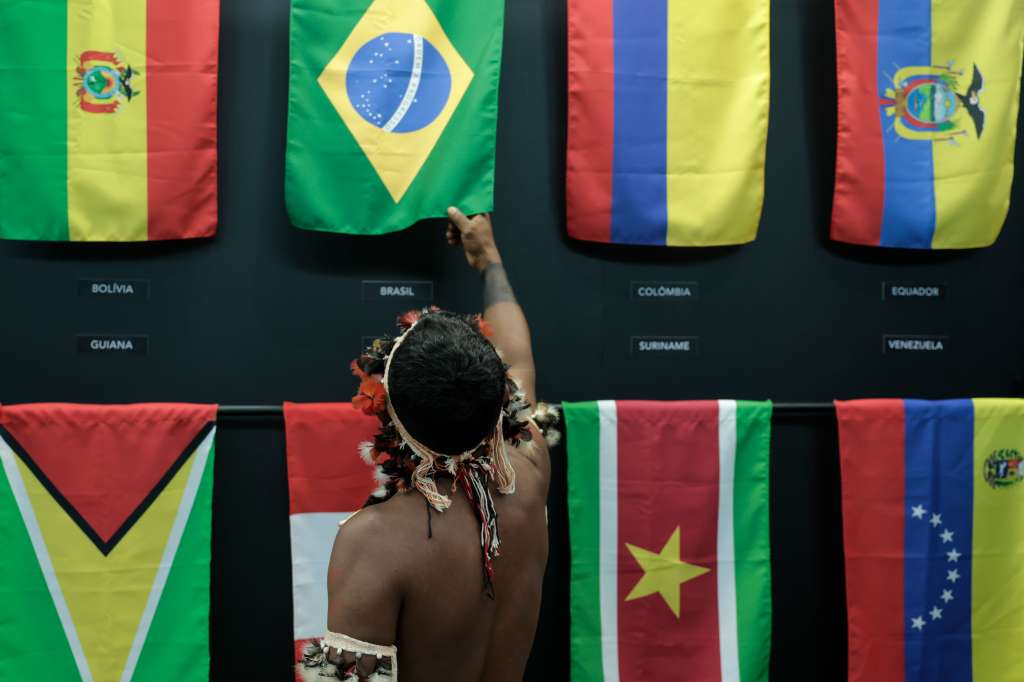 -FOTODELDÍA- AME8530. BELÉM (BRASIL), 06/08/2023.- Un indígena toca en la bandera de Brasil hoy, durante los Diálogos Amazónicos en Belém (Brasil). Las recomendaciones, divulgadas en el marco de los Diálogos Amazónicos que concluyen este domingo y preceden a la cumbre de mandatarios de la región amazónica, buscan el reconocimiento y la protección de las tribus no contactadas, que se estima son 185 repartidas a lo largo y ancho del mayor bosque tropical del planeta. EFE/ Antonio Lacerda