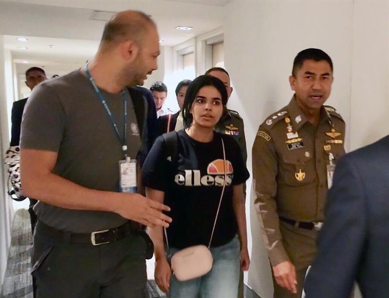 La joven saudí, Rahaf Mohammed Al-Qunun, conversa con el jefe de la policía de inmigración de Tailandia, Surachet Hakparn, y un trabajador de ACNUR antes de abandonar el aeropuerto Suvarnabhumi en Tailandia el lunes, 7 de enero de 2018. / EFE.