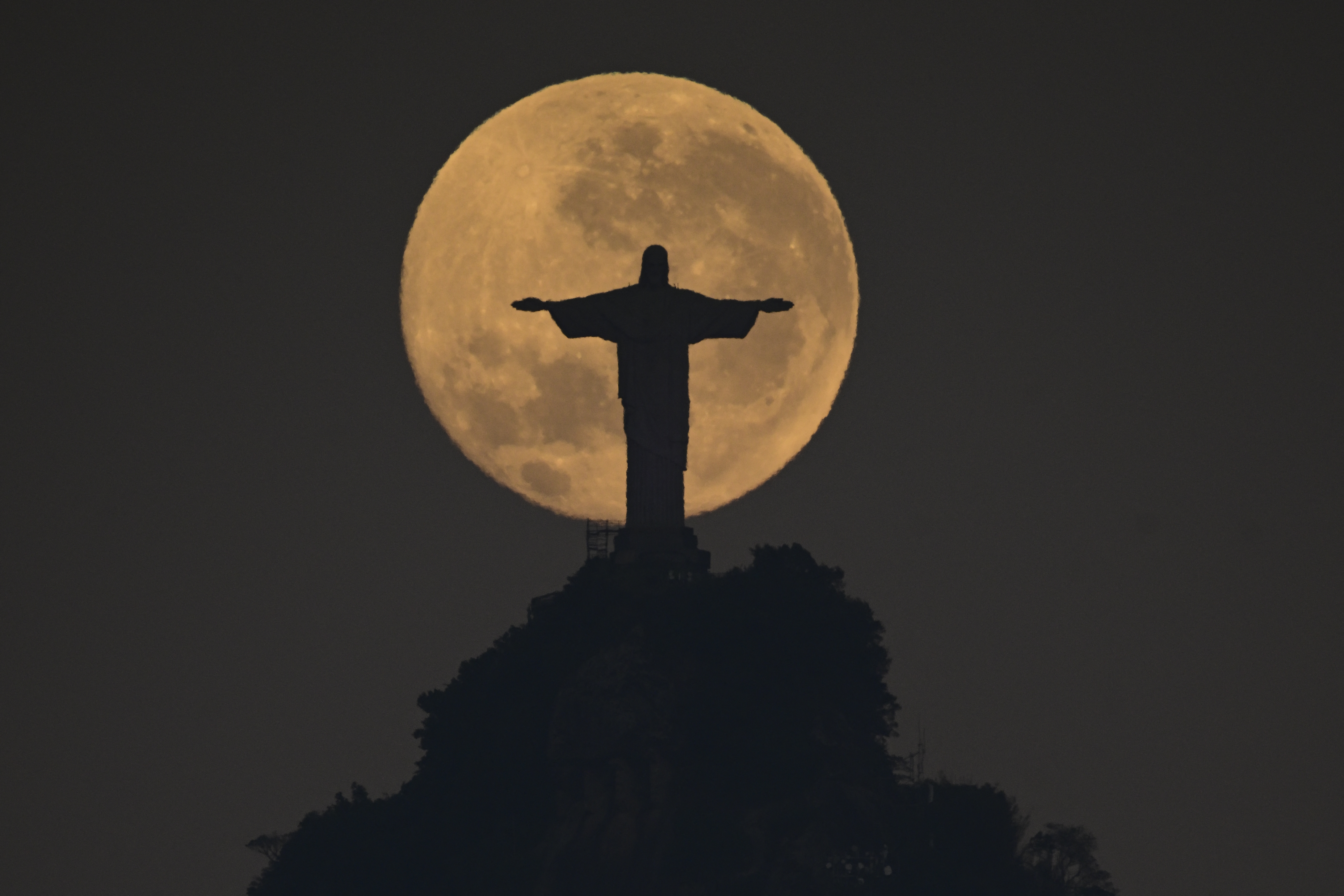 Superluna detrás de la estatua del Cristo Redentor en Río de Janeiro. (Photo by Pablo PORCIUNCULA / AFP)