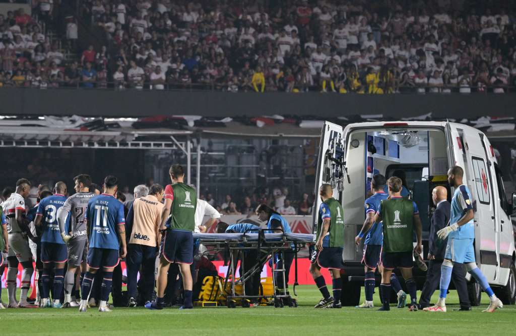 El defensa de Nacional Juan Manuel Izquierdo (cubierto) recibe atención médica tras desmayarse durante el partido de fútbol de vuelta de octavos de final de la Copa Libertadores entre Sao Paulo de Brasil y Nacional de Uruguay en el estadio MorumBIS de Sao Paulo