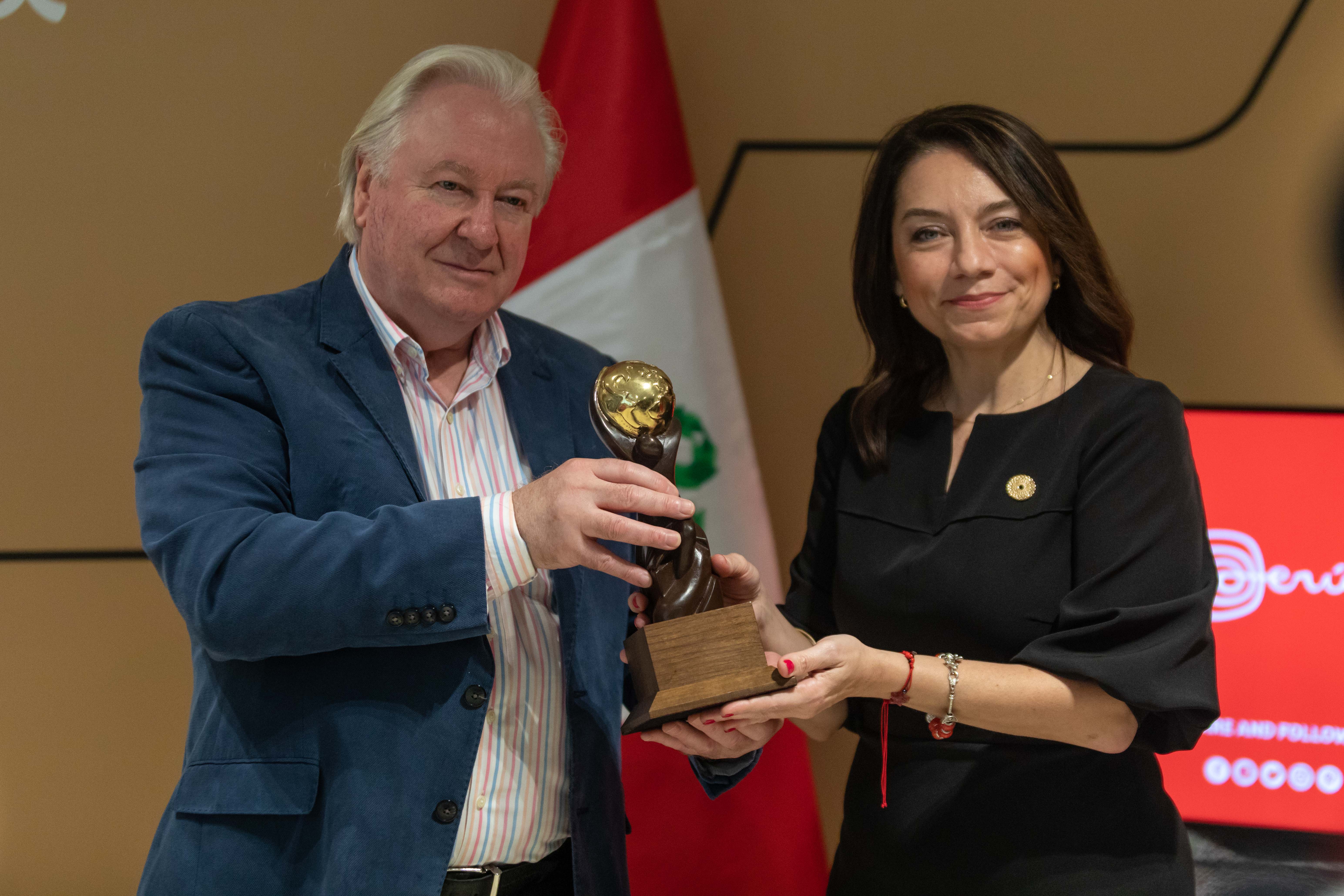 Graham Cooke, fundador de los WTA, le entrega a Amora Carbajal, presidenta ejecutiva de Promperú, el reconocimiento de Machupicchu, como Atracción turística líder de Suramérica.