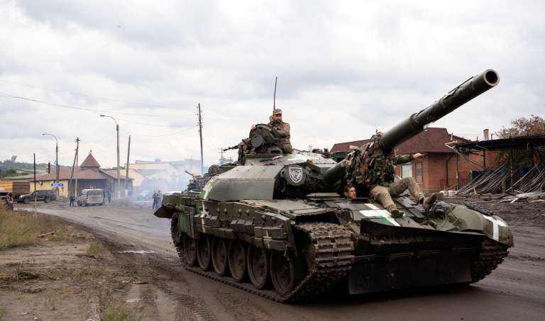 Militares ucranianos pasan sobre un tanque en la ciudad recuperada de Izyum. Para su sorpresa, el ejército ucraniano ha podido apropiarse de cientos de materiales de guerra en perfecto estado que las tropas rusas dejaron abandonados.
