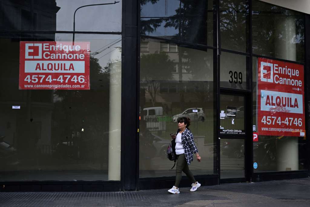 A woman walks next to a commercial establishment with rent price signs on a street in Buenos Aires on June 13, 2024.
