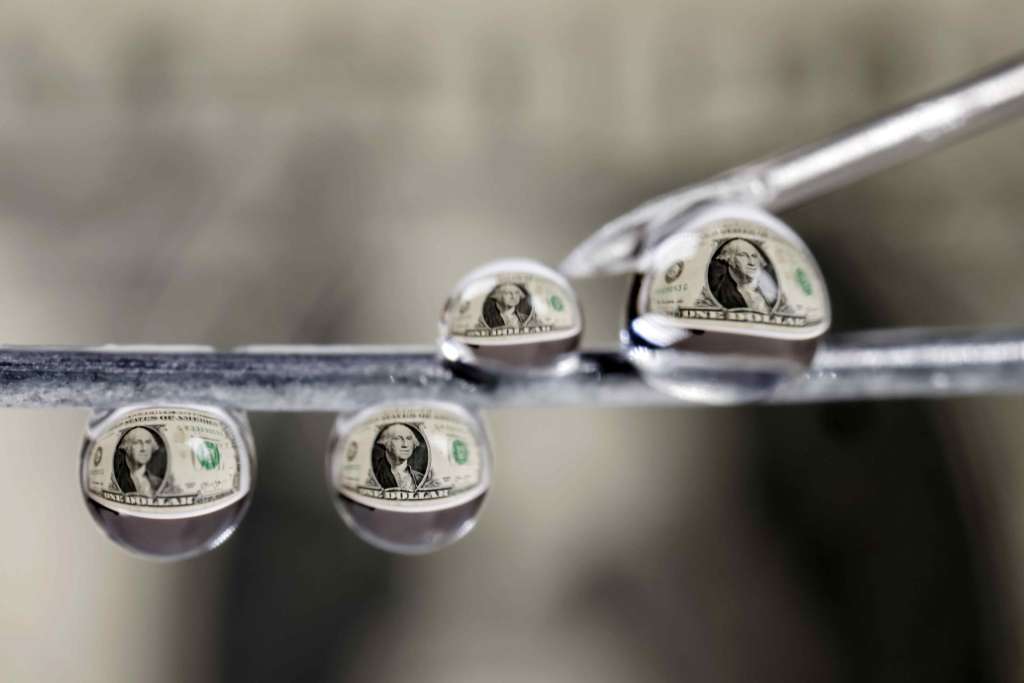 FOTODELDÍA AME3813. SAN JOSÉ (COSTA RICA), 30/09/2025.- Fotografía que muestra billetes de un dolar reflejados en gotas de agua este lunes, en San José (Costa Rica). La expansión y normalización de los esquemas de préstamos informales en Costa Rica se han convertido en una amenaza para la seguridad ciudadana ya que se combina con otros fenómenos como la usura, la extorsión y, en muchos casos, la violencia, alertó este martes un informe de la Organización de las Naciones Unidas (ONU). EFE/ Jeffrey Arguedas