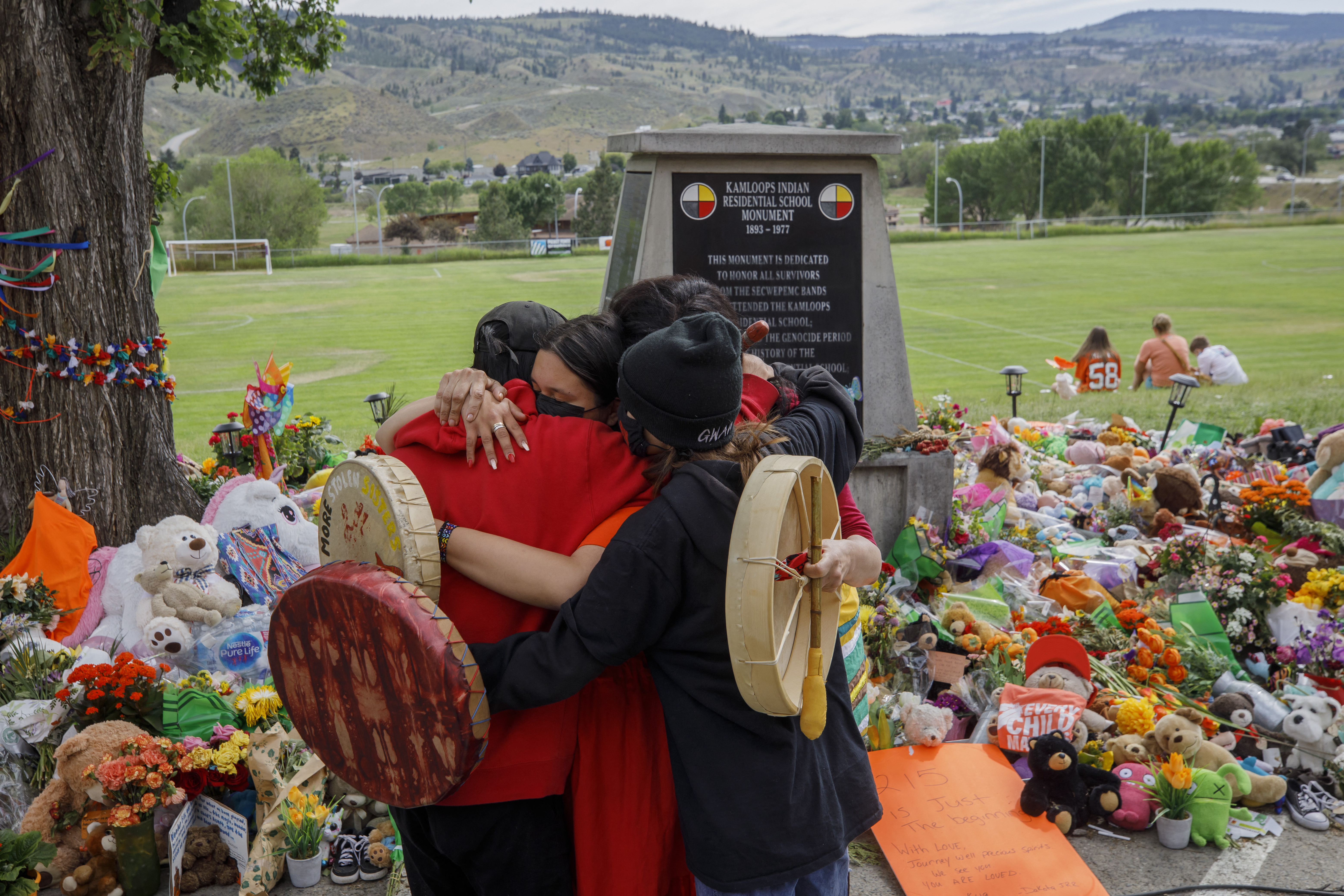 Personas de Mosakahiken Cree Nation se abrazan frente a un memorial improvisado en la antigua escuela residencial india de Kamloops para honrar a los 215 niños.