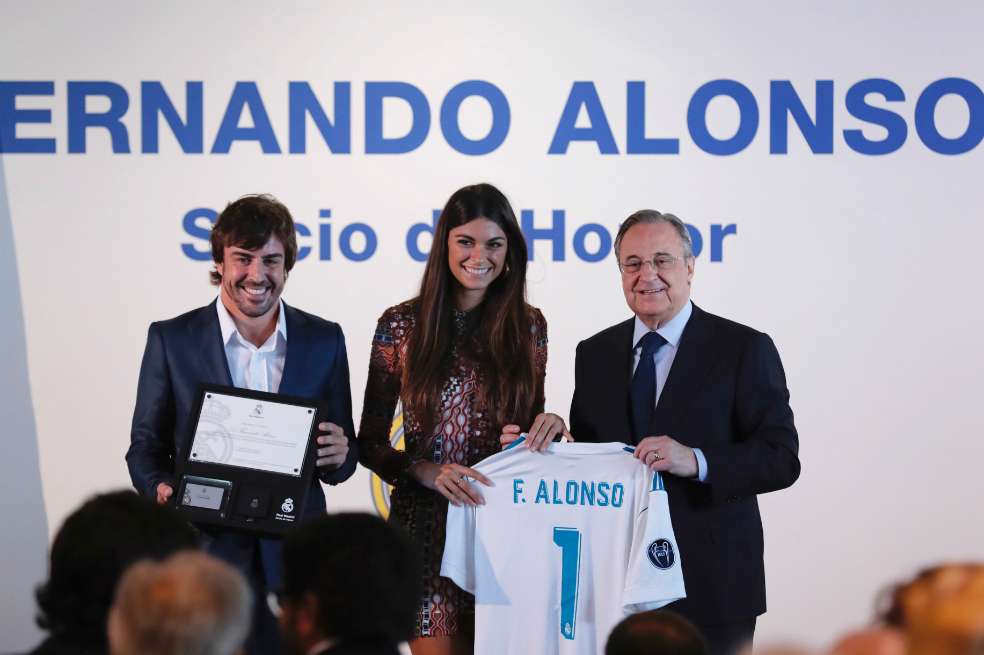 El piloto Fernando Alonso (i), acompañado de su novia, Linda Morselli, recibió del presidente de Real Madrid, Florentino Pérez (d), una camiseta con su nombre y el número 1. / EFE