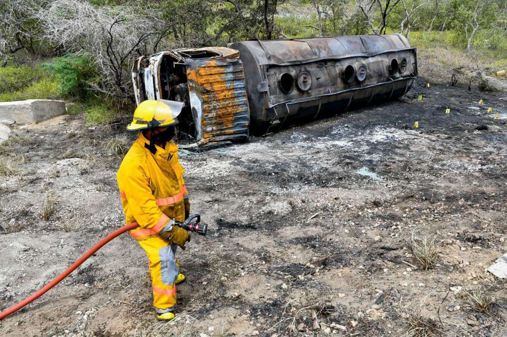Handout picture released by the Gobernacion de Magdalena showing a firefighter next to the remains of a tanker truck carrying fuel that caught fire, in Pueblo Viejo, north of Bogota, Colombia on July 6, 2020. - At least seven people died and another 46 suffered burns following the explosion of a truck carrying fuel on a highway in northern Colombia, authorities reported. (Photo by Handout / GOBERNACION DE MAGDALENA / AFP) / RESTRICTED TO EDITORIAL USE - MANDATORY CREDIT "AFP PHOTO / GOBERNACION DE MAGDALENA " - NO MARKETING - NO ADVERTISING CAMPAIGNS - DISTRIBUTED AS A SERVICE TO CLIENTS