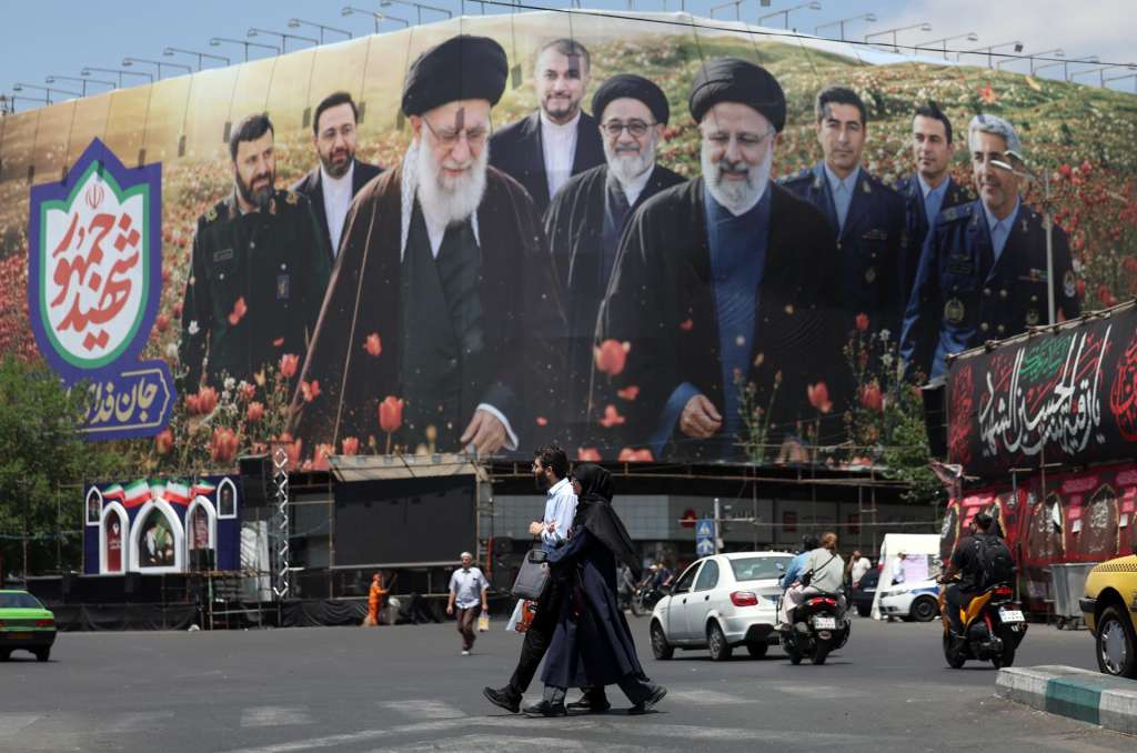 FOTODELDÍA Teherán (Irán ), 21/05/2026.- Ciudadanos iraníes caminan frente a una gran valla publicitaria con imágenes del difunto líder supremo iraní, el ayatolá Ali Jamenei, y del difunto presidente iraní, Ebrahim Raisi, en la plaza Enghelab de Teherán, Irán, este jueves. Las tensiones entre Estados Unidos e Irán continúan al no haberse alcanzado un acuerdo.EFE/ Abedin Taherkenareh