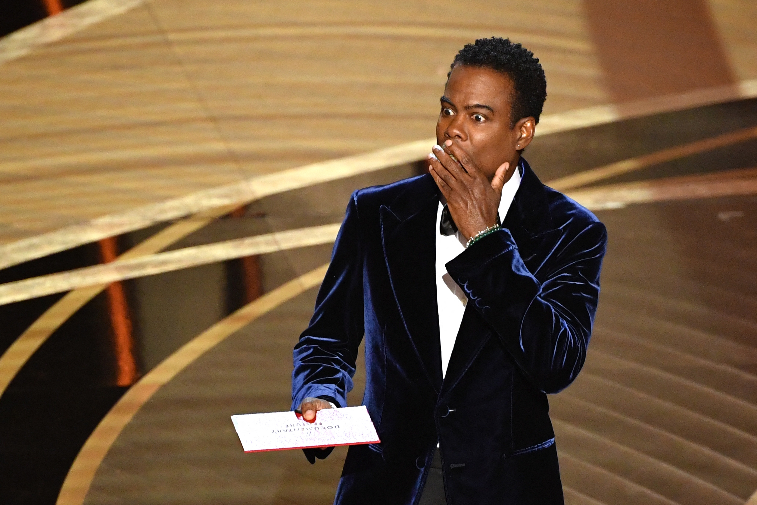 En esta foto de archivo tomada el 27 de marzo de 2022 el actor estadounidense Chris Rock habla en el escenario durante la 94ª edición de los Oscar en el Dolby Theatre de Hollywood, California. - Chris Rock finalmente devolvió el golpe a Will Smith el 4 de marzo de 2023 en una brutal rutina de stand-up, un año después de que el actor lo abofeteara frente a una audiencia televisiva mundial para los Oscar.