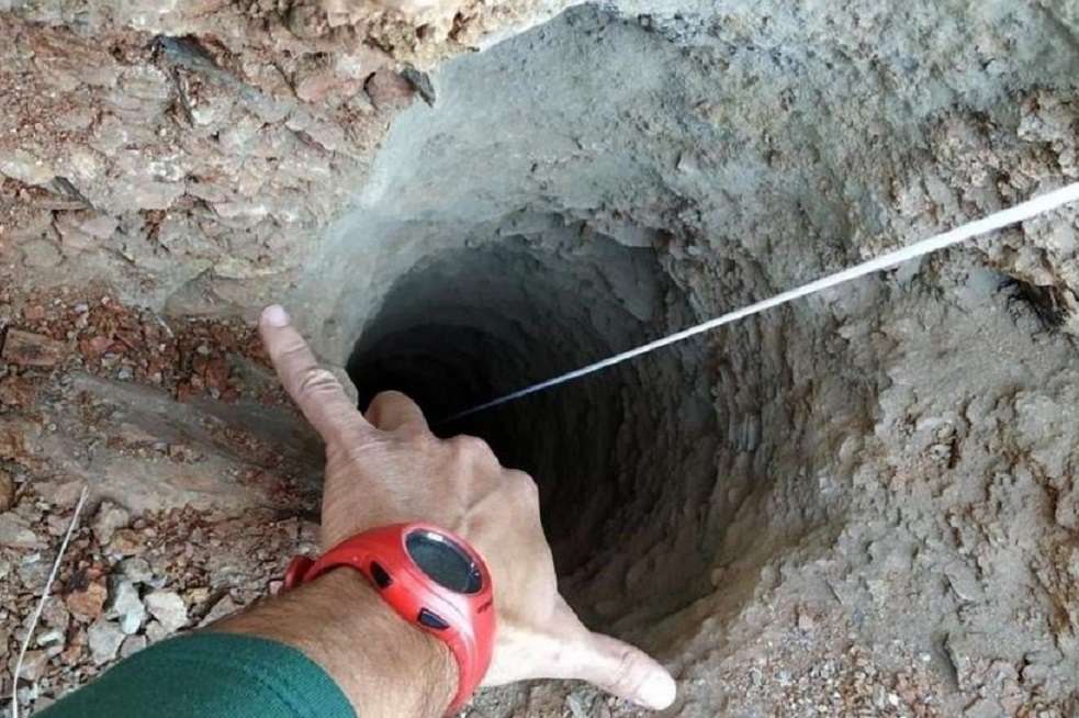 Un guardia civil señala el orificio, de apenas 30 centímetros de ancho, del pozo de más de 100 metros de profundidad por el que cayó un niño de dos años. / EFE