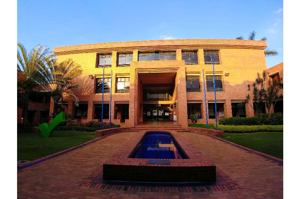 Biblioteca de la Universidad ICESI. El edificio está rodeado de palmeras y la luz del sol cae sobre él.