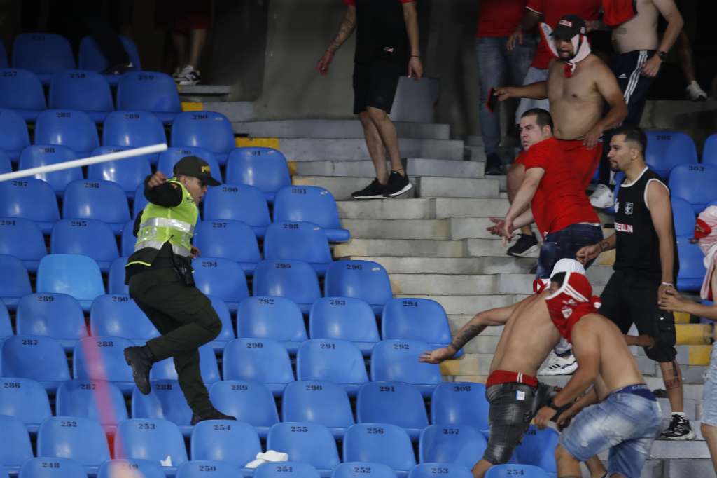 AME5628. CALI (COLOMBIA), 15/12/2024.- Un policía huye de aficionados del América durante unos disturbios en el partido de vuelta de la final de Copa Colombia entre América y Atlético Nacional, este domingo en el Estadio Pascual Guerrero, en Cali (Colombia). EFE/ Ernesto Guzmán