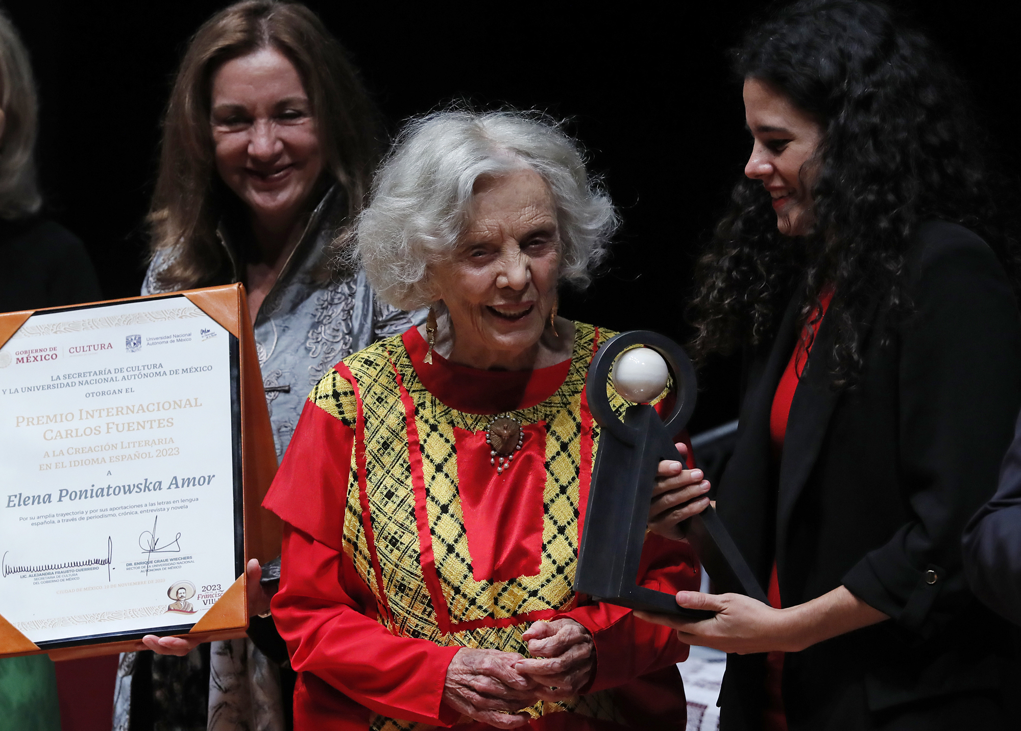 MEX1438. CIUDAD DE MÉXICO (MÉXICO), 09/11/2023.- La escritora mexicana Elena Poniatowska (c) recibe de manos de la secretaria de Gobernación, María Luisa Alcalde (d), el Premio Internacional Carlos Fuentes a la Creación Literaria en el Idioma Español de 2023, hoy, en Ciudad de México (México). La escritora y periodista Elena Poniatowska recibió este jueves el Premio Internacional Carlos Fuentes a la Creación Literaria en el Idioma Español de 2023, lo que equiparó con recibir “un boleto para subir a las alas del Ángel de la Independencia” y, así, “subir al cielo”. EFE/Mario Guzmán