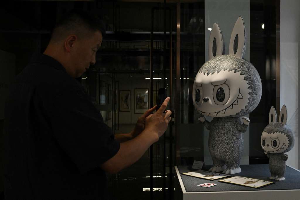 A man takes picture of limited-edition Labubus on display in Beijing on June 20, 2025, ahead of an auction by the Yongle Auction house on June 22. (Photo by Adek BERRY / AFP)