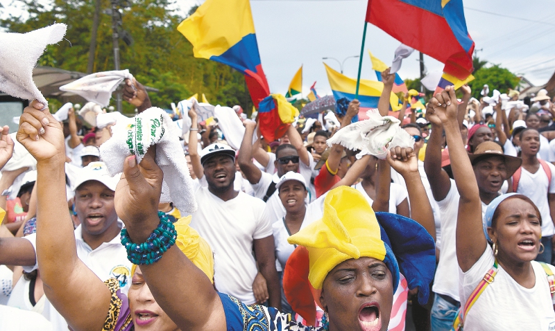 Personas de todas las edades salieron ayer a marchar con camisas blancas y banderas de Colombia. / AFP