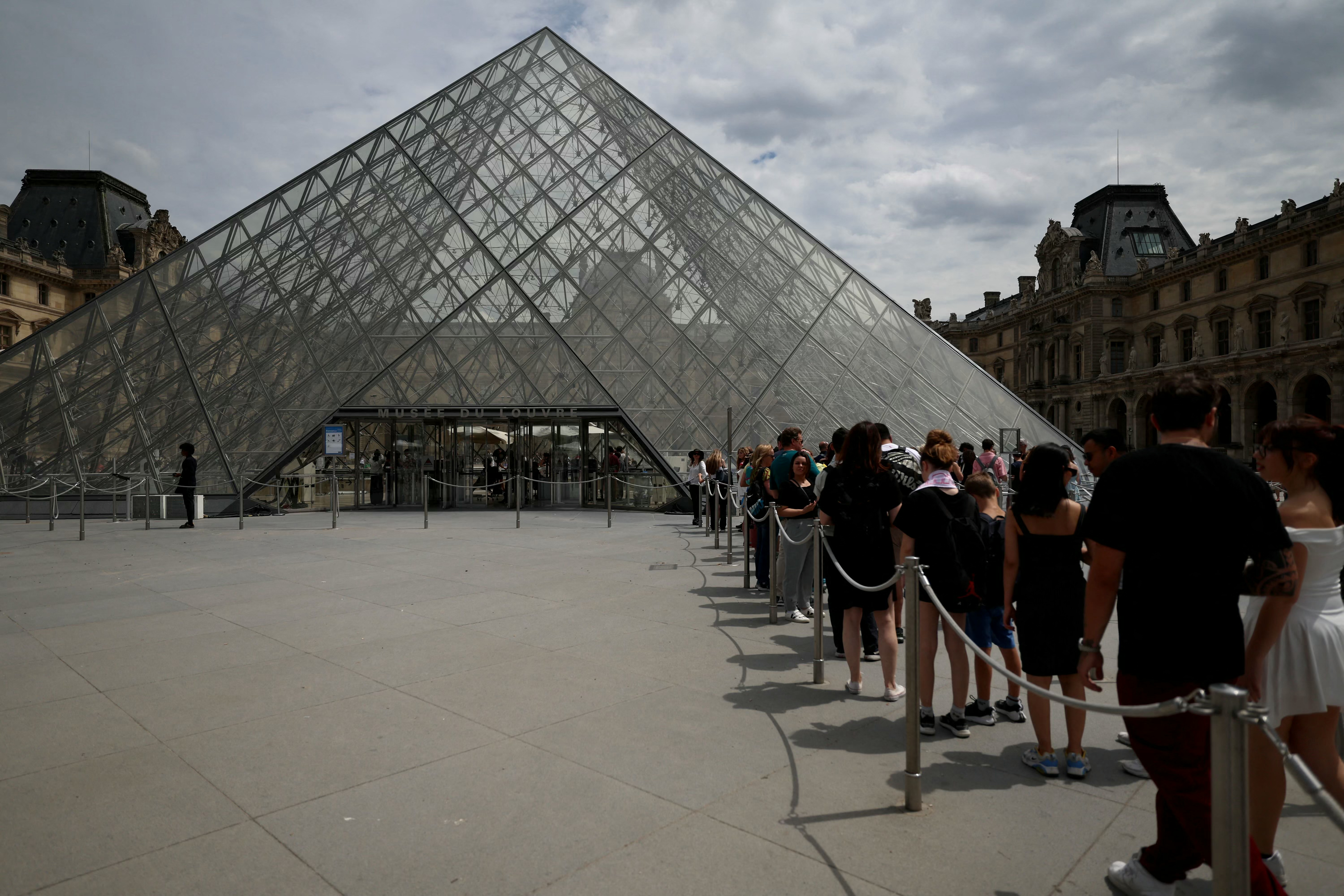 (FILES) Visitors line up in front of the Louvre Pyramid designed by Ieoh Ming Pei at the Louvre Museum in Paris on July 11, 2024.