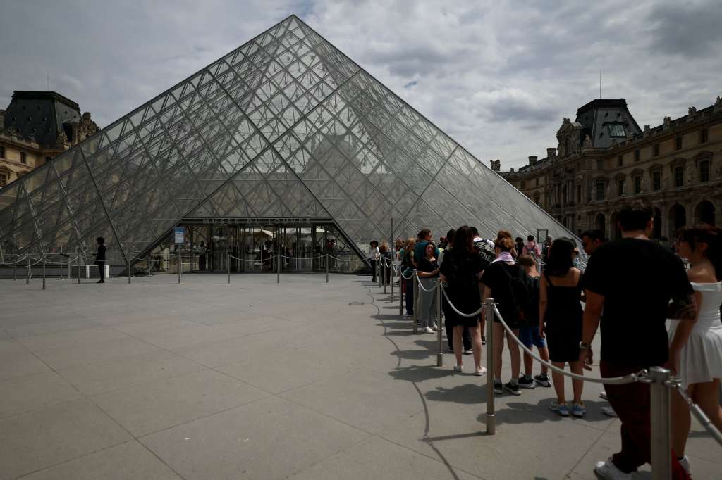 (FILES) Visitors line up in front of the Louvre Pyramid designed by Ieoh Ming Pei at the Louvre Museum in Paris on July 11, 2024.