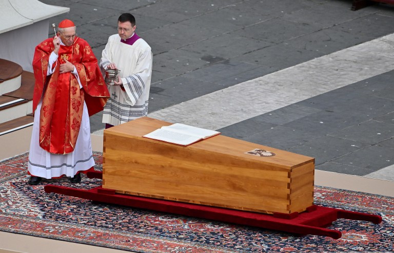 El cardenal italiano Giovanni Battista Re bendice el ataúd que lleva el cuerpo de Benedicto XVI, quien se desempeñó como papa entre 2005 y 2013, cuando renunció.