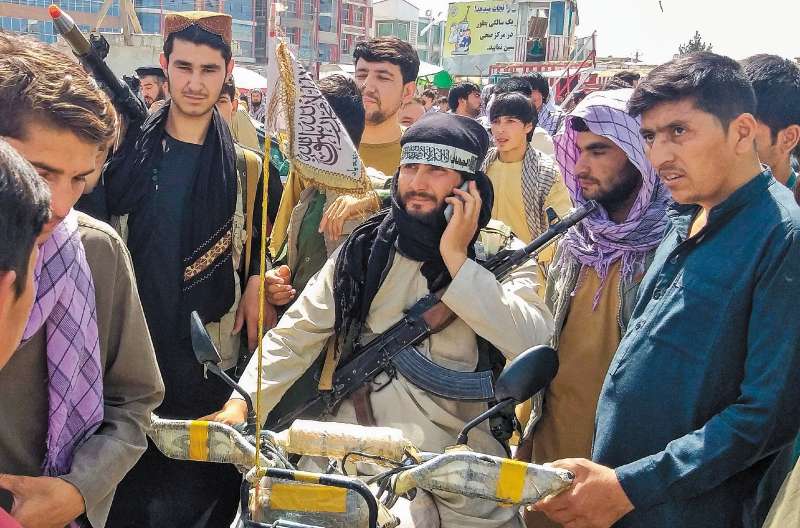 Un talibán rodeado de personas en la ciudad de Pul-e-Khumri, capital de la provincia de Baghlan. El lugar está a unos 200 kilómetros de Kabul. / AFP