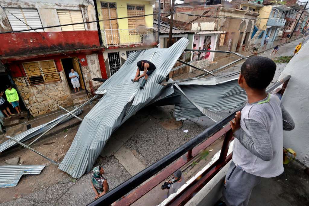 AME3128. SANTIAGO DE CUBA (CUBA), 29/10/2025.- Personas recogen escombros en una calle afectada por el paso del huracán Melissa este miércoles, en Santiago de Cuba (Cuba). Melissa se aleja de Cuba convertido en un huracán de categoría 2, con vientos máximos sostenidos de hasta 160 kilómetros por hora, y comienza a dirigirse hacia las Bahamas tras provocar inundaciones, crecidas de ríos y corrimientos de tierras en el oriente de Cuba. EFE/ Ernesto Mastrascusa