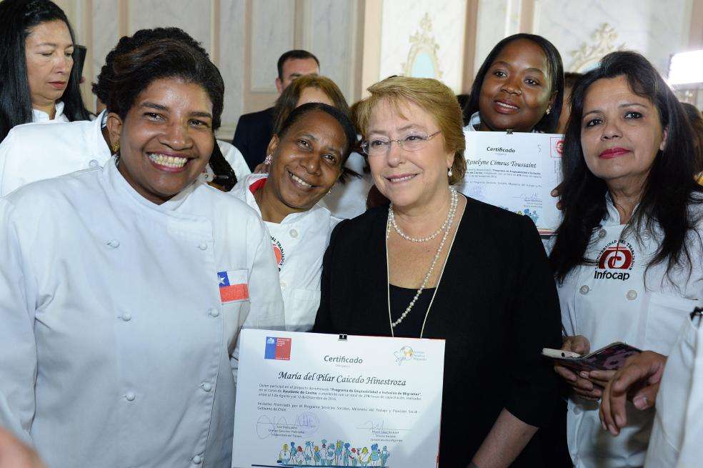 La presidenta de Chile, Michelle Bachelet, con un grupo de migrantes que se acaban de graduar de programas técnicos.  / EFE