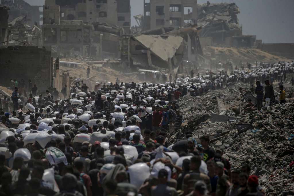 ZIKIM (-), 27/07/2025.- Internally displaced Palestinians carry bags of flour near a food distribution point in Zikim, northern Gaza Strip, 27 July 2025. The Israeli army declared a 'tactical pause' in military operations in parts of the Gaza Strip on 27 July, to facilitate the safe passage of humanitarian aid convoys. More than 130 Palestinians, the majority of whom children, have died of malnutrition in the Gaza Strip, the Palestinian Ministry of Health said on 27 July. EFE/EPA/MOHAMMED SABER