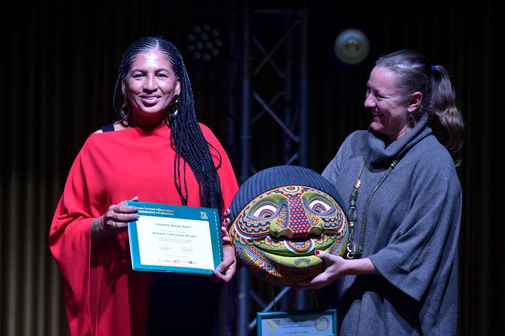 Lidera el Consejo Comunitario General del San Juan (Acadesan) (vestido rojo), recibe de Helena Storm, embajadora de Suecia en Colombia (vestido gris), el premio a la defensora del año, del Premio Nacional de Derechos Humanos XII 2023 en Colombia.