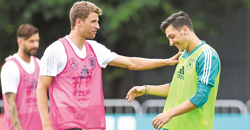 El delantero Thomas Müller conversa con el volante Mesut Özil en la práctica de Alemania, ayer. / AFP