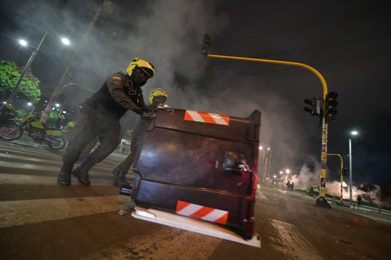 Un policía corre un contenedor de basura en la vía