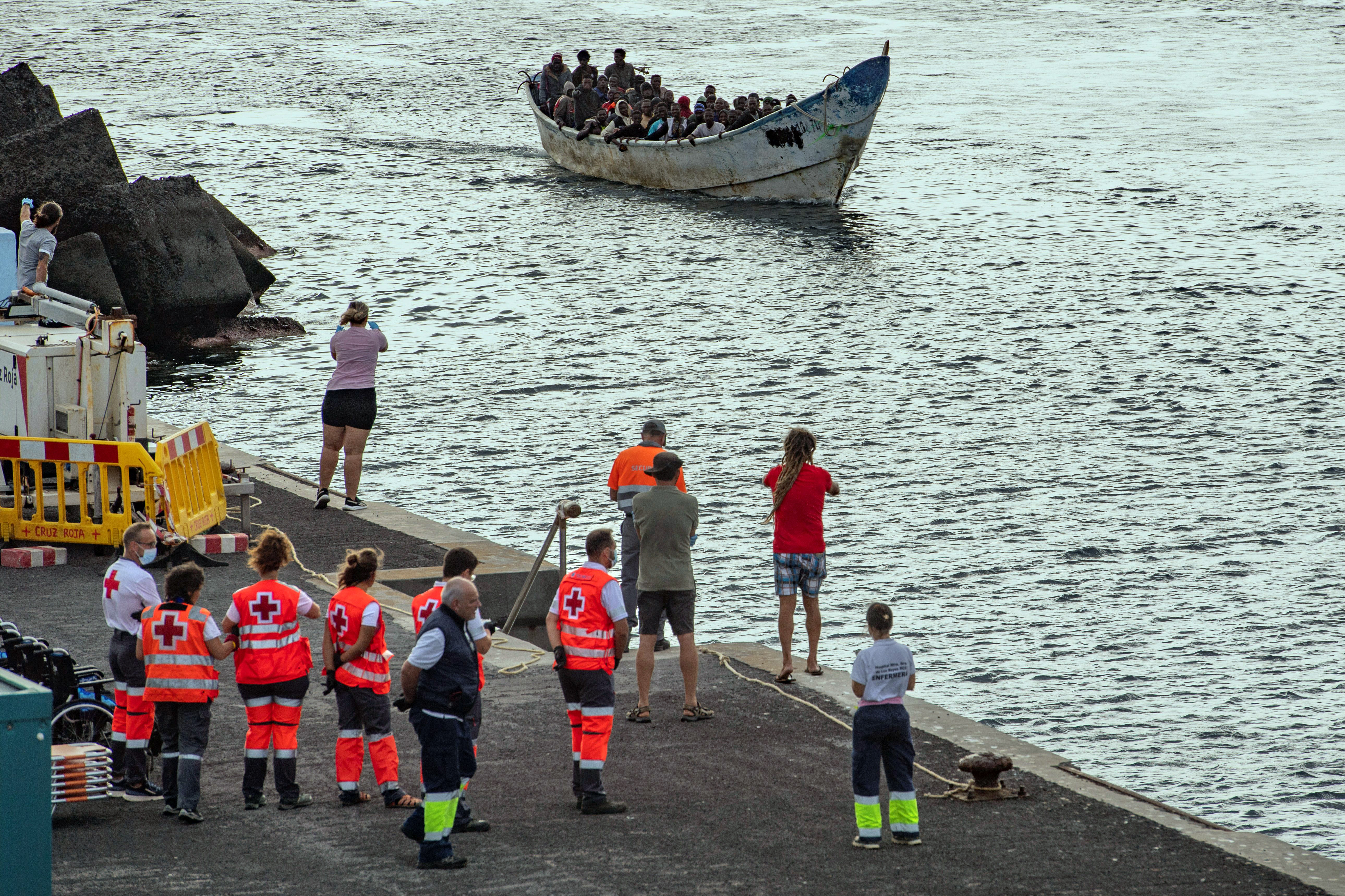 (FILES) Members of the Spanish Red Cross stand as a 'cayuco' boat with 54 migrants onboard arrives at La Restinga port on the Canary island of El Hierro, on September 15, 2024.