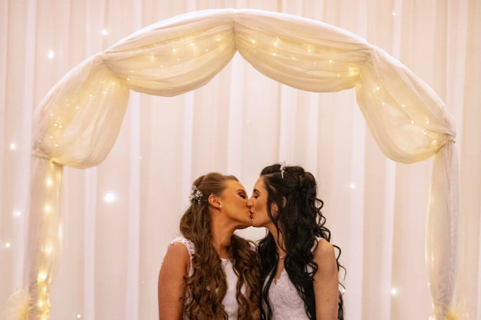 Robyn Peoples (izquierda) y Sharni Edwards (derecha) se besan mientras posan para fotografías después de convertirse en la primera pareja del mismo sexo en casarse en Irlanda del Norte.