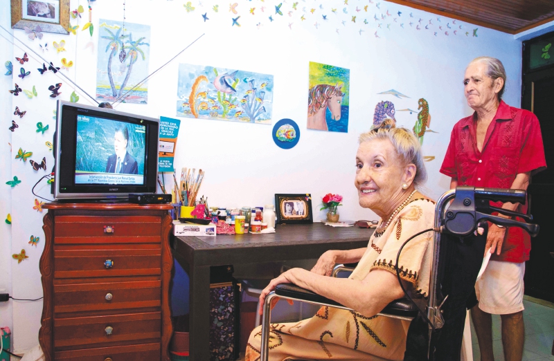 Dina Merlín, que vive en la casa de adultos mayores San Pedro Claver de San Andrés, es una de los beneficiarios de los más de cuatro mil dispositivos de televisión digital terrestre. Al fondo su esposo Saúl. / Cortesía
