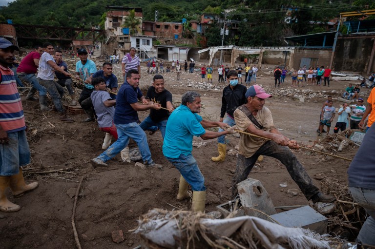ACOMPAÑA CRÓNICA: VENEZUELA LLUVIAS***AME3304. LAS TEJERÍAS (VENEZUELA), 09/10/2022.- Habitantes colaboran hoy para retirar los destrozos tras el desbordamiento de la quebrada Los Patos, en Las Tejerías, estado Aragua (Venezuela). Algunos habitantes de Las Tejerías, en la zona central de Venezuela, recuerdan este domingo los gritos de la tragedia, mientras otros son incapaces de describir la noche del sábado, cuando esta pequeña ciudad fue arrasada por una quebrada desbordada, que se llevó a más de un centenar de personas, de las que, al menos, 25 murieron y más de 50 siguen desaparecidas. EFE/ Rayner Peña R
