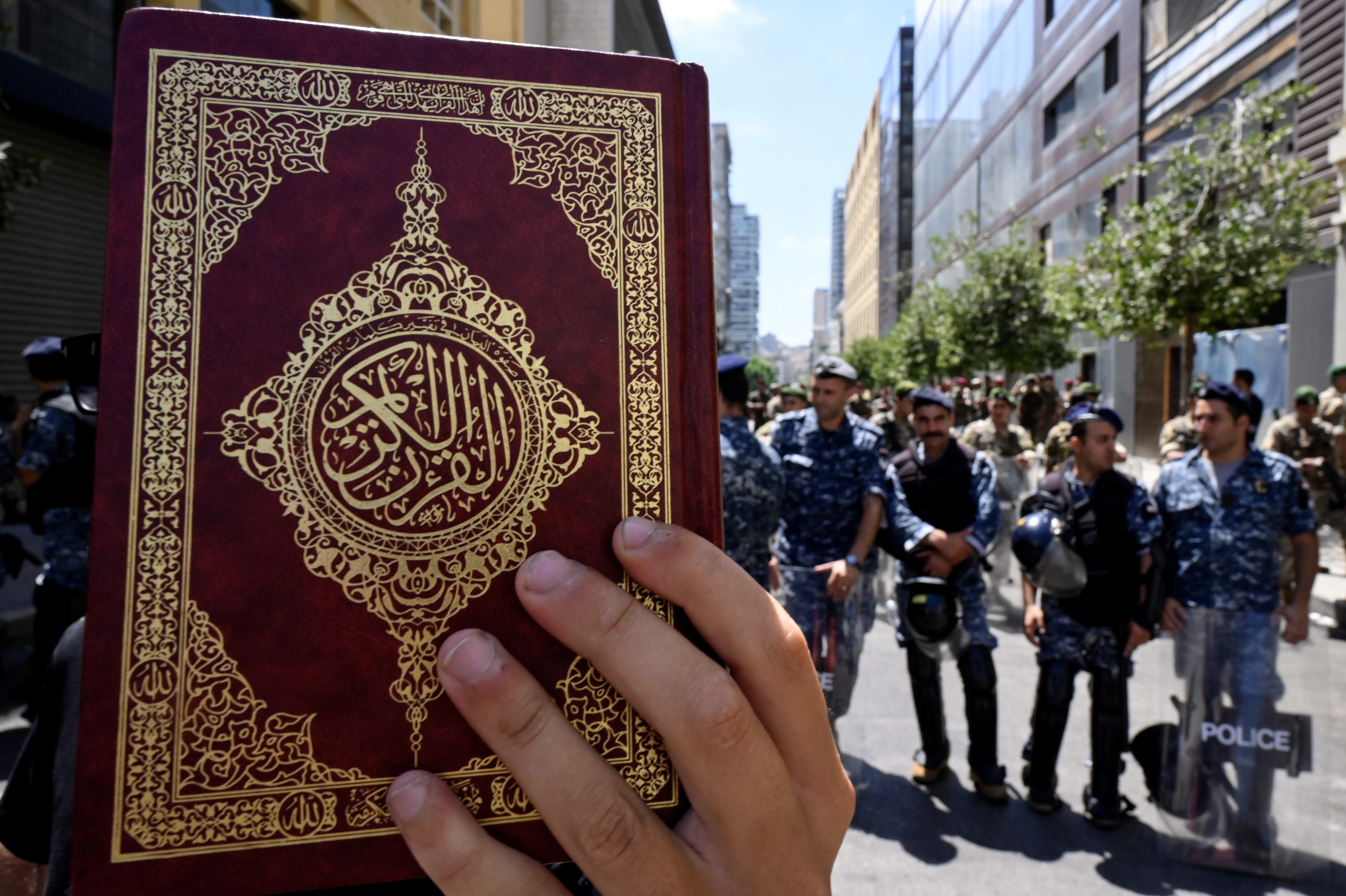 Beirut (Lebanon), 21/07/2023.- Lebanese police officers stand guard as a protester holds a copy of the Koran outside Sweden's embassy after Hezbollah leader called for protests outside mosques against the Koran desecration, in Beirut, Lebanon, 21 July 2023. Hezbollah leader Hassan Nasrallah called for protests outside mosques following Friday prayers to condemn what he called the desecration of the Koran in Sweden by anti-Islam protesters. (Protestas, Líbano, Suecia) EFE/EPA/WAEL HAMZEH